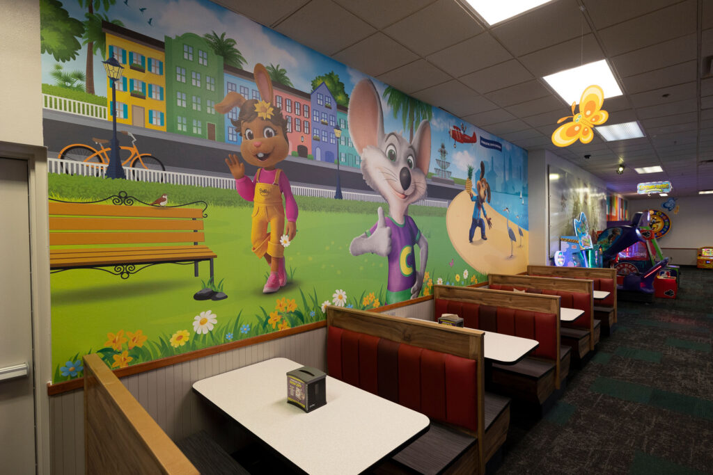 Dining area at Chuck E. Cheese with a colorful mural and welcoming atmosphere.
