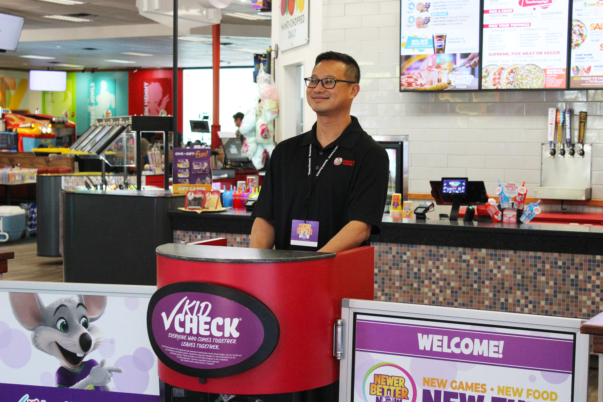 Chuck E. Cheese team member smiling and welcoming guests at the front desk