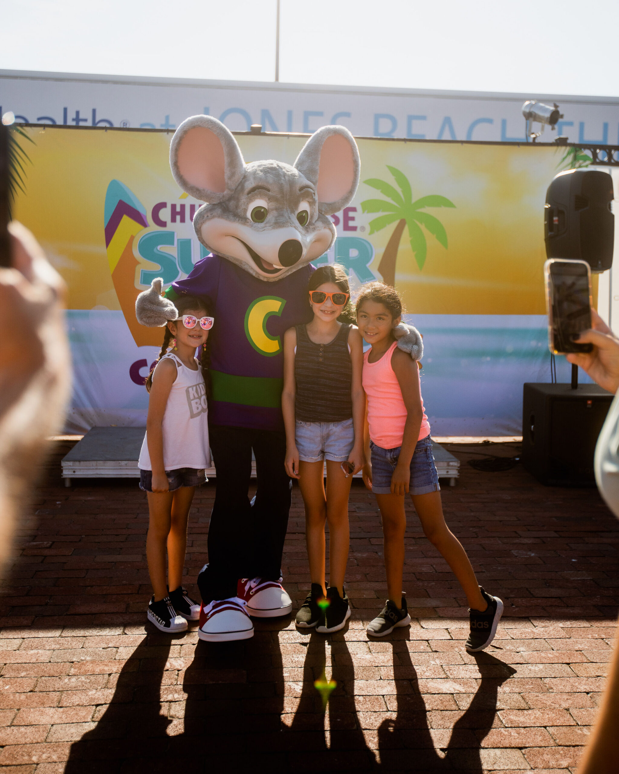 Chuck E. Cheese with smiling kids at a summer event