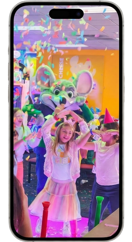 Kids dancing with Chuck E. Cheese as colorful confetti falls during a birthday party celebration.