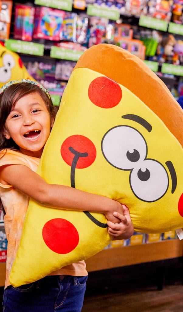 Girl hugging a large pizza plush at the prize counter