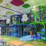 Kids playing and climbing in the multi-level Chuck E. Cheese Adventure World play structure.